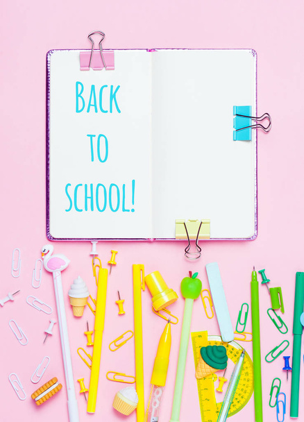 Colorful pink background with various School accessories are laid out in the form of a rainbow. Empty notebook. Flat lay top view. Study arrangement, making wish list or plans. Back to school text. - Φωτογραφία, εικόνα
