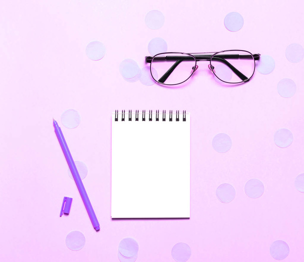 Notebook or notepad with eye glasses and headphones on pink backgriund. Creative minimalism chancery concept. Top view, flat lay. - Foto, Bild