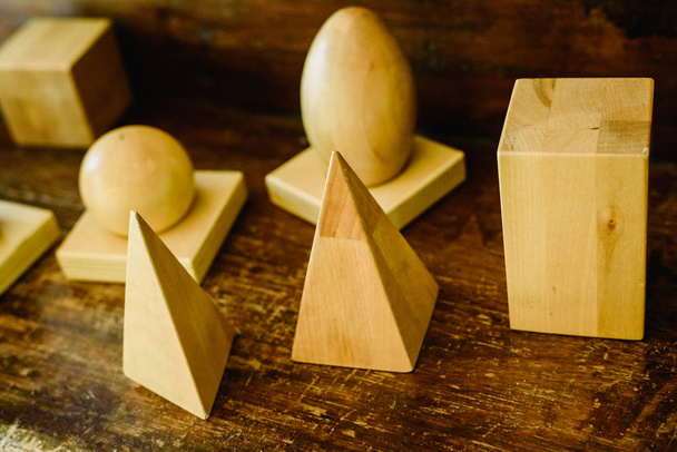 Formes en bois massif pour étudier la géométrie et les volumes, cônes, triangles, carrés, sphères sur un fond de bois chaud
. - Photo, image