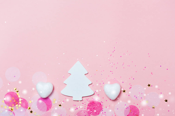 New year greeting card in pink colors with confetti and white christmas tree and hearts. Top view, flat lay, Copyspace for your text. Christmas bright concept. - Foto, Imagem