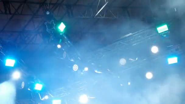 雨の中で光と煙のコンサート。サーチライト ステージ上の明るい黄色と青ビーム。ぼやけています。背景映像. - 映像、動画