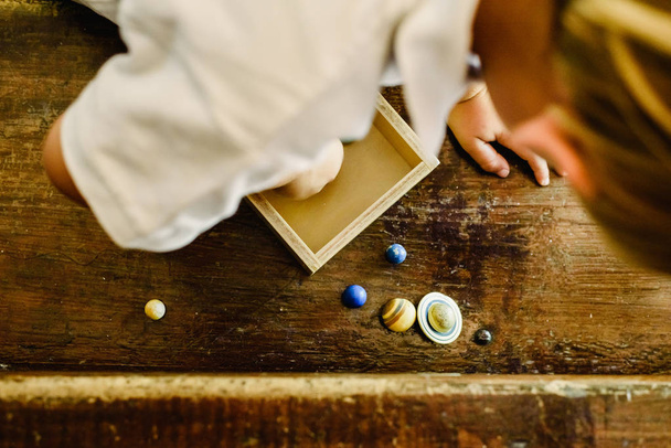 Gyermek játszó kis játék bolygók egy régi fából készült asztal. - Fotó, kép