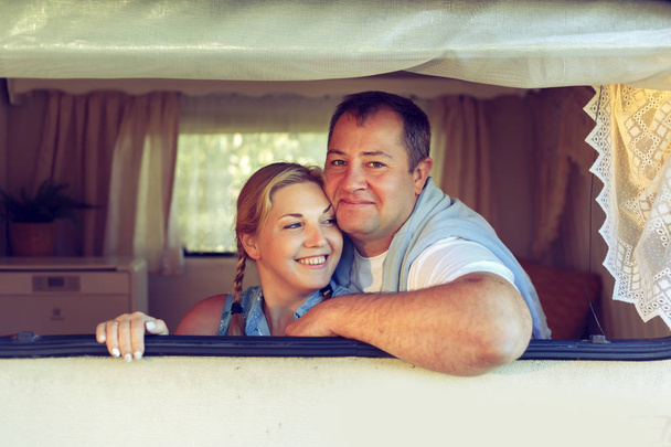Happy couple of tourists sitting in a camper van on a summer day. Vintage, toned. - Foto, Imagen