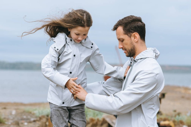 family portrait of dad and dauther in raincoat near the sea - Фото, зображення