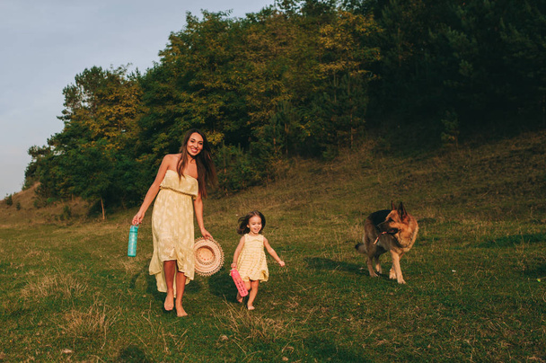 young mother walk with her little daughter, and their dog - Фото, изображение