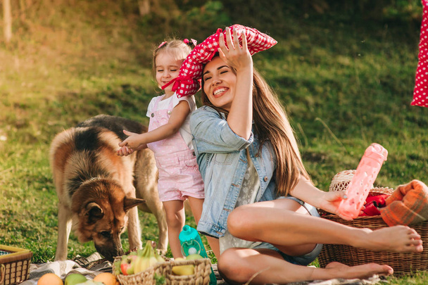 young mother and her daughter at a picnic with a German shepherd dog - Photo, Image