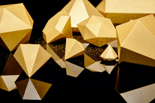 блискучі фігурні золоті шматочки, відображені на чорному фоні
 - Фото, зображення