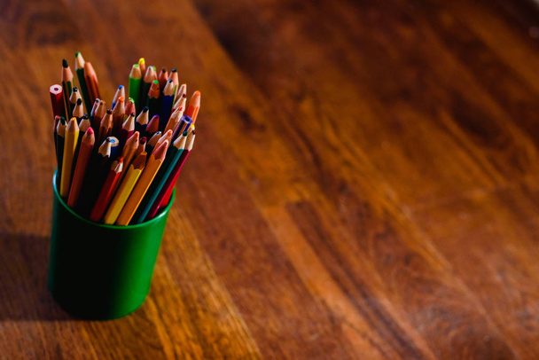 Värilliset kynät täydellä kynällä, lattialla lämmin puu tausta ja vapaata tilaa tekstiä
 - Valokuva, kuva