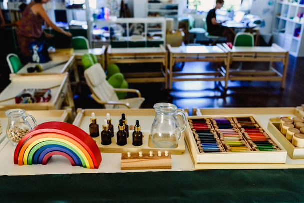Tavolo e scaffalature con materiale montessori, arcobaleno colorato in aula
. - Foto, immagini