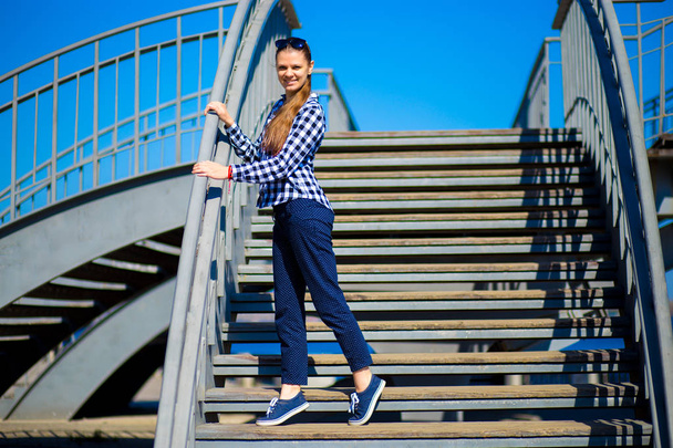 Young stylish girl stands on street stairs in sunny day. Street style - Fotoğraf, Görsel