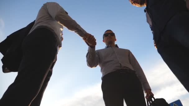 Three businessmen farewell with each other each other and farewell and diverge in different directions. Colleagues shake hands with blue sky at city background. Business handshake outdoor. Slow motion - Footage, Video