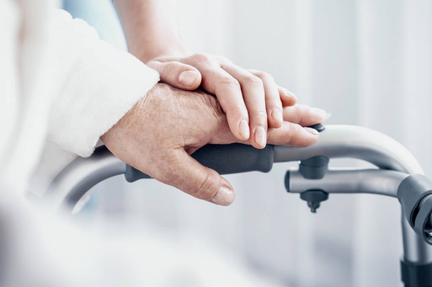 Close-up on senior person hand on walking frame and supporting caregiver - 写真・画像