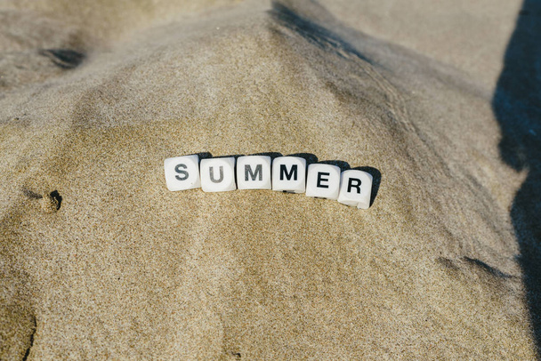 Conceito de verão feito com dados com letras na areia molhada de uma praia e motivos marinhos
. - Foto, Imagem