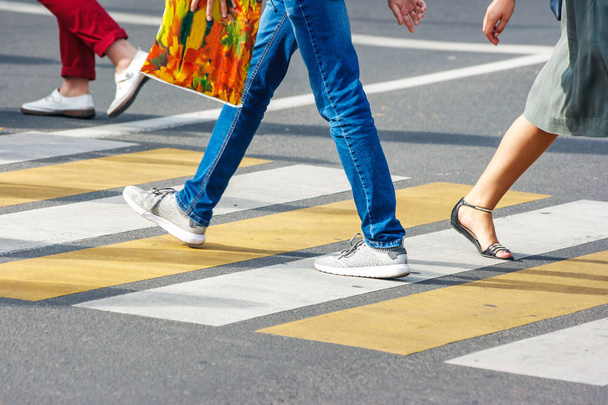 Wiele nóg ludzi przekraczających przejście dla pieszych w ruchliwej ulicy śródmieścia w słoneczny letni dzień - Zdjęcie, obraz