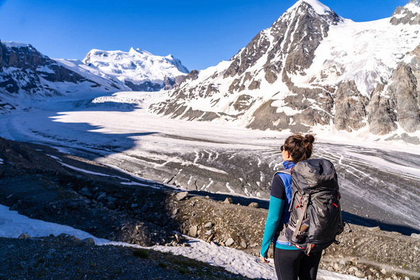 Young female hiker looking at Glacier de Corbassiere. Hiking a mountain trail around Glacier and Grand Combin in Valais Alps (Pennine Alps), Switzerland. - Фото, зображення