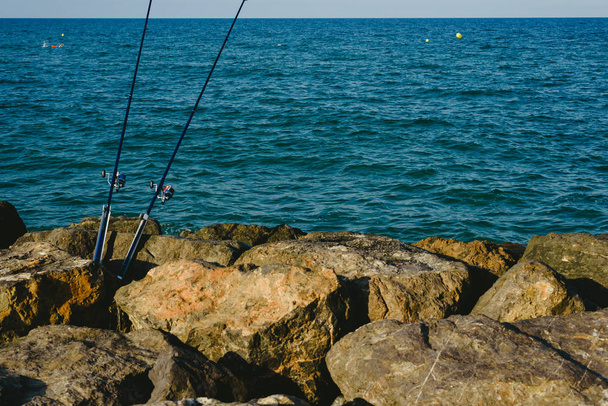 Fishing rods fixed to the rocks near the sea coast without fishermen - Photo, Image