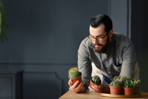 Hipster met baard tuinieren bedrijfsvoering met cactussen - Foto, afbeelding