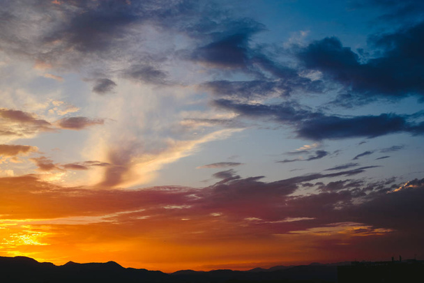 Piękny zachód słońca słońce odcieniach koloru pomarańczowego, za górami i błękitne niebo - Zdjęcie, obraz