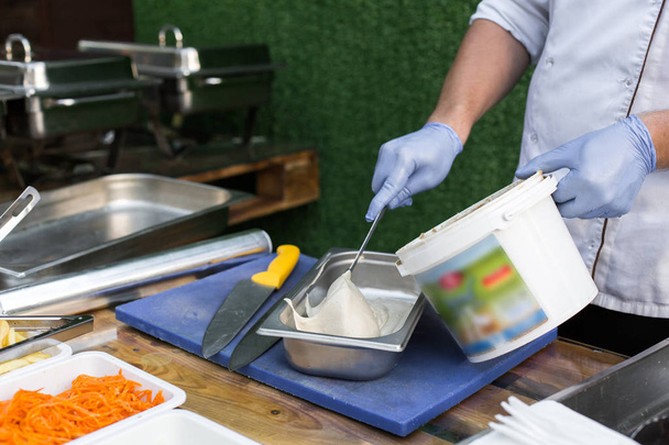 kucharz w niebieskie rękawice na ulicy stawia hummus przygotować falafel w metalowe pudełko - Zdjęcie, obraz