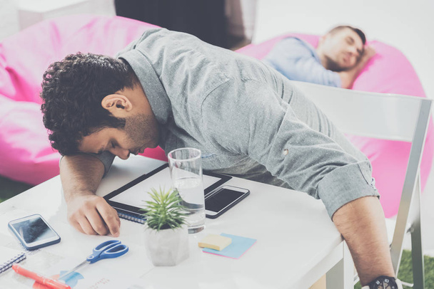 junge Geschäftsleute schlafen auf dem Tisch und Hocker im modernen Büro, Business-Teamwork - Foto, Bild