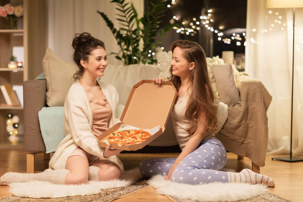 happy female friends with pizza at home - Foto, afbeelding