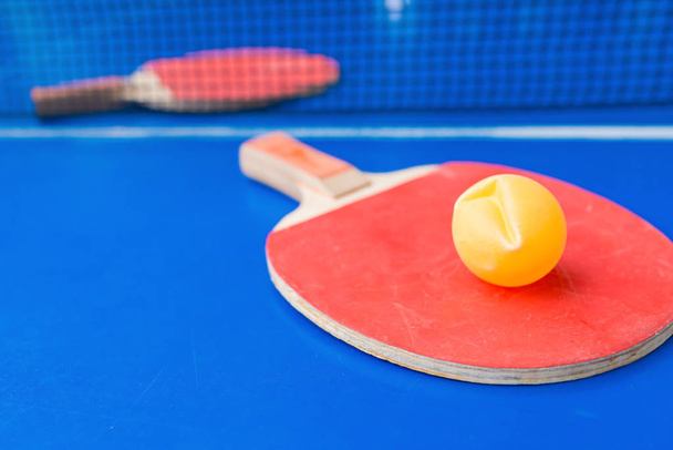 pingpong rackets en bal en net op een blauwe pingpong tafel - Foto, afbeelding