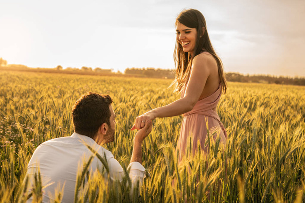 wirst du mich heiraten? Männer machen seiner Freundin auf dem Feld Heiratsantrag - Foto, Bild