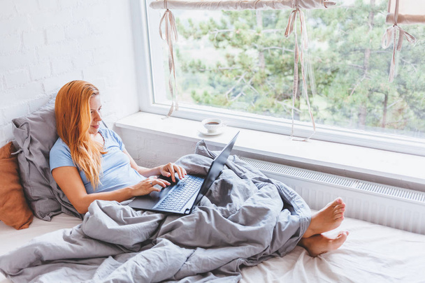 Woman working in bed on laptop early in the morning - Photo, Image