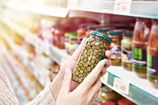Buyer hands with a can of canned capers in the store - Foto, imagen