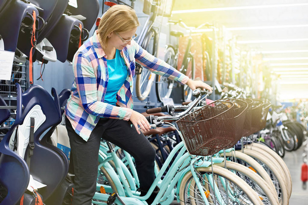 Woman chooses bicycle in sports store - Foto, Bild