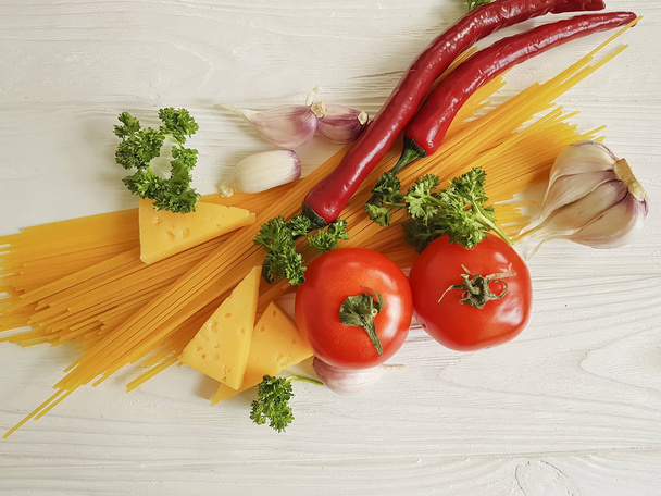 спагетти, помидоры, чеснок, сыр на белом деревянном фоне, приготовление пищи
 - Фото, изображение