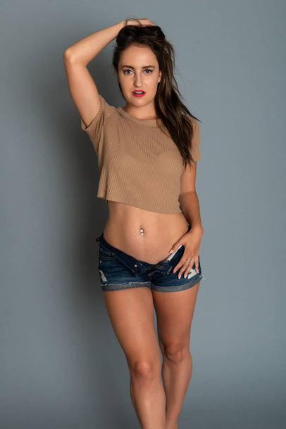 Beautiful petite brunette in a tan knit top and denim shorts - Foto, Imagen