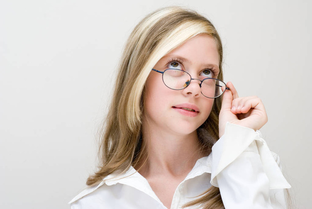 pretty teen girl wearing white blouse and eyeglasses posing on light background, back to school concept - Photo, image