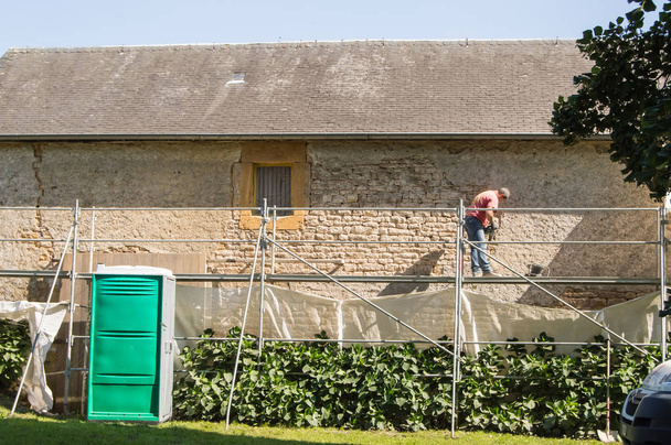 Pierres nues d'une façade avec des marteaux piqueurs par deux ouvriers de macon sur un échafaudage
 - Photo, image
