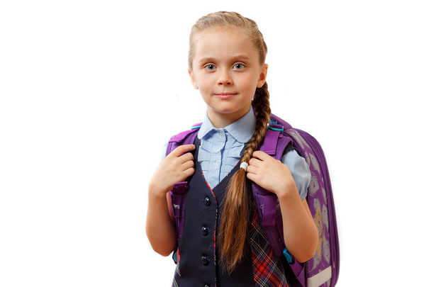 Happy cute beautiful blond schoolgirl wearing school uniform, holding checkered backpack with textbooks, posing, friendly smiling, isolated studio shot, white background - Photo, image