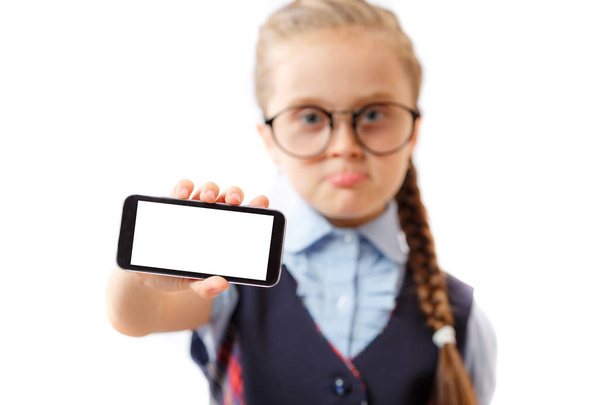 Σχολείο κορίτσι δείχνει ένα mockup οθόνης έξυπνο τηλέφωνο που απομονώνονται σε λευκό φόντο - Φωτογραφία, εικόνα