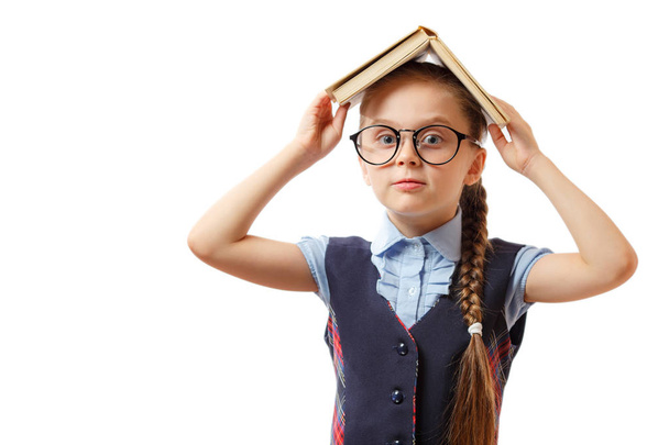 Tiener meisje met boek over haar hoofd. Geïsoleerd op witte achtergrond - Foto, afbeelding