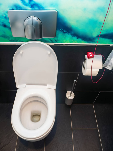 weiße Keramik-Toilettenschüssel im Inneren der Toilette im Krankenhaus, roter Knopf für Schwesternruf - Foto, Bild
