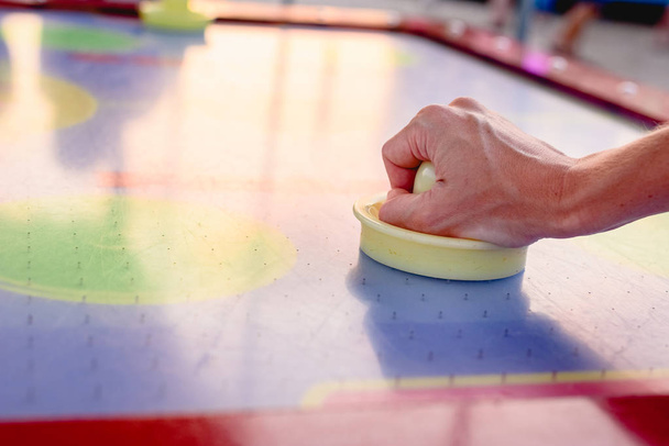 Hand holding a stick to hit disc in the table air hockey game. - Photo, Image