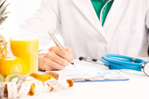 Nutritionniste écrivant des dossiers médicaux et des ordonnances avec des fruits frais
 - Photo, image