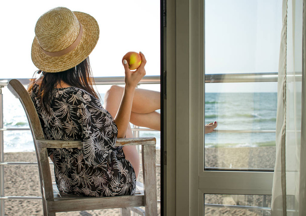 Una chica con una manzana mirando al mar
 - Foto, imagen