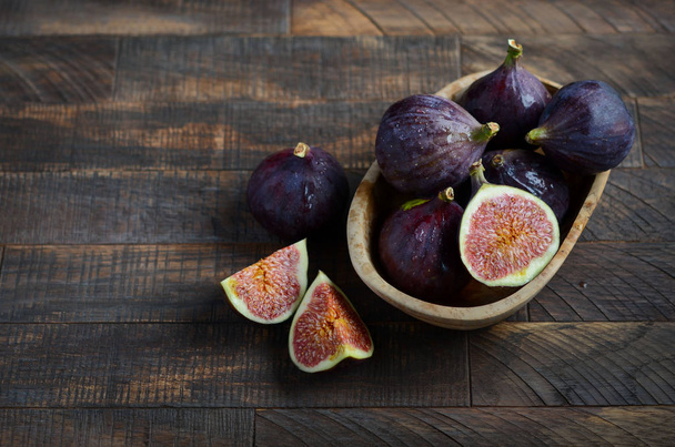 Fresh figs in a wooden bowl on an old wooden background. - Photo, Image