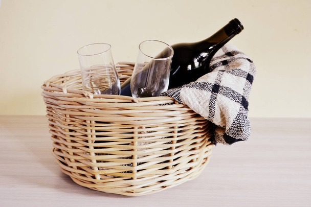 wicker picnic basket with a blanket, bottle of wine, bread and glasses on a light background - Photo, Image