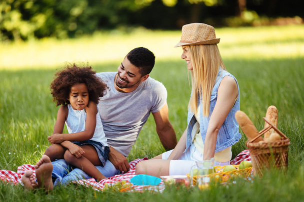 Picture of lovely couple with their daughter having picnic in nature - Foto, imagen