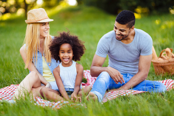 Picture of lovely couple with their daughter having picnic in nature - Фото, изображение