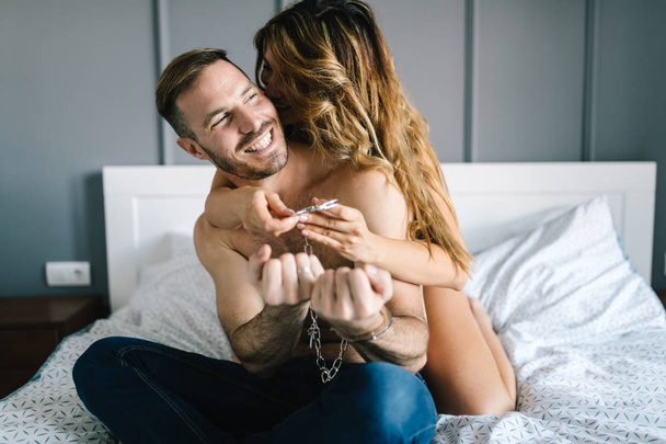 Passionate beautiful couple in bedroom enjoying foreplay - Фото, изображение