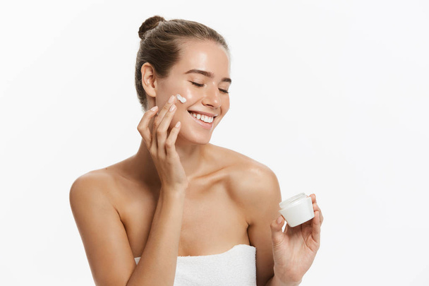 Kaunis nuori nainen soveltamalla kosmeettinen kerma hoito hänen kasvonsa eristetty valkoisella pohjalla
 - Valokuva, kuva
