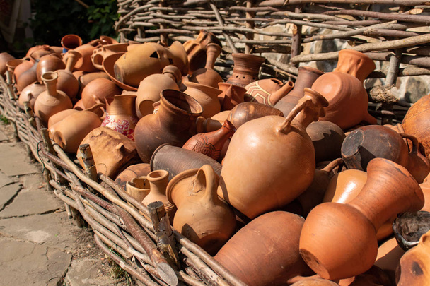 Many ceramic handmade utensils, made of clay, hanging on wattle fence - Foto, imagen