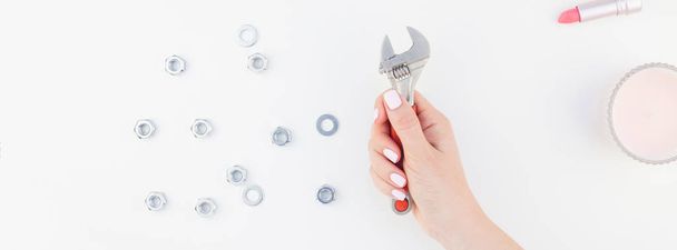 Creative long wide banner of woman hand pastel manicure polish holding spanner with copy space nuts and cosmetics isolated white background in minimalism style. Repair or improvement feminism concept - Photo, Image
