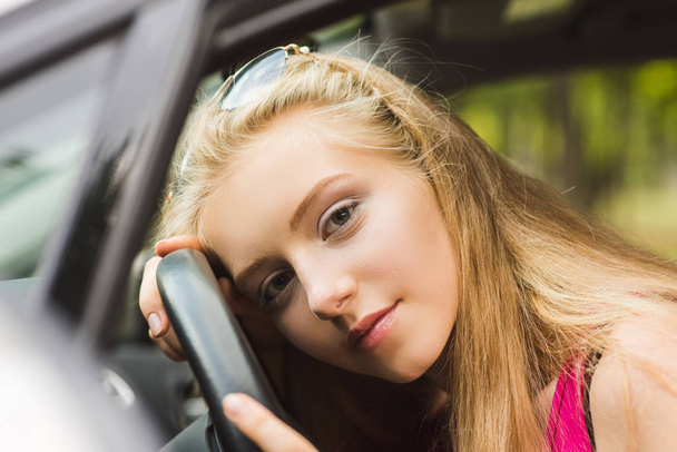 Girl head on steering wheel inside car - Photo, Image